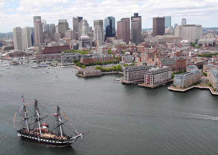 USS Constitution sailing in Boston Harbor with the Massachusetts city skyline behind